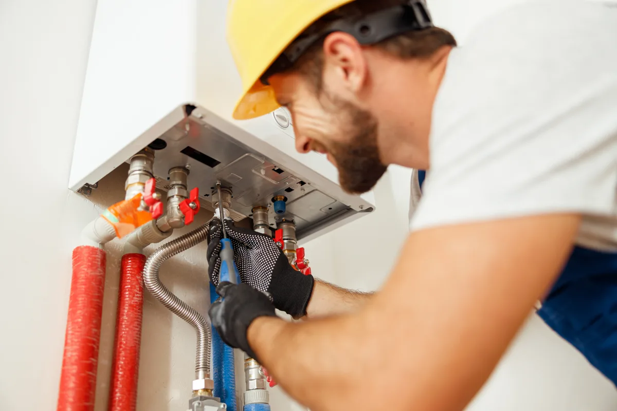 Plumber using a screwdriver on a boiler