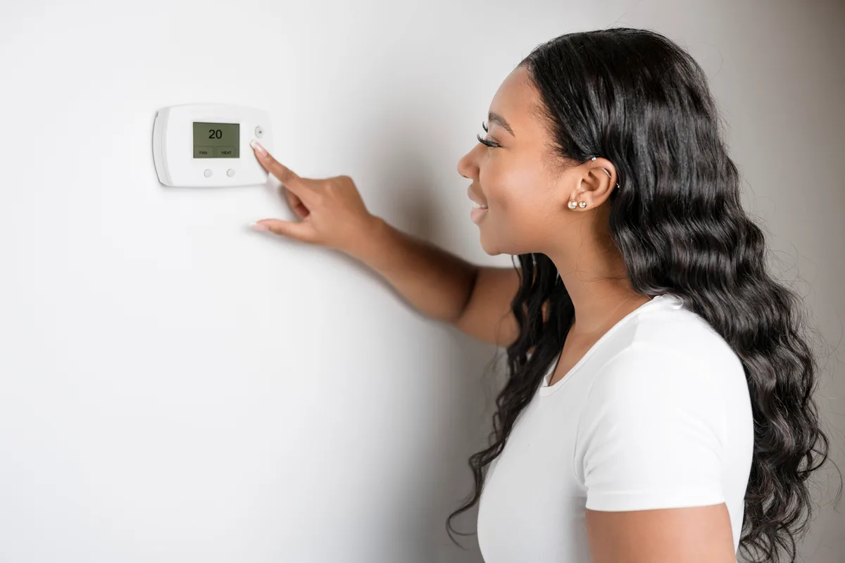 Woman adjusting a wall thermostat